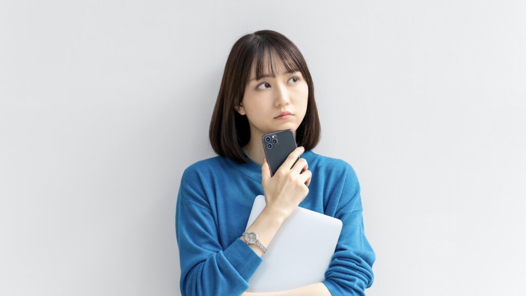 スマホを持って悩む女性