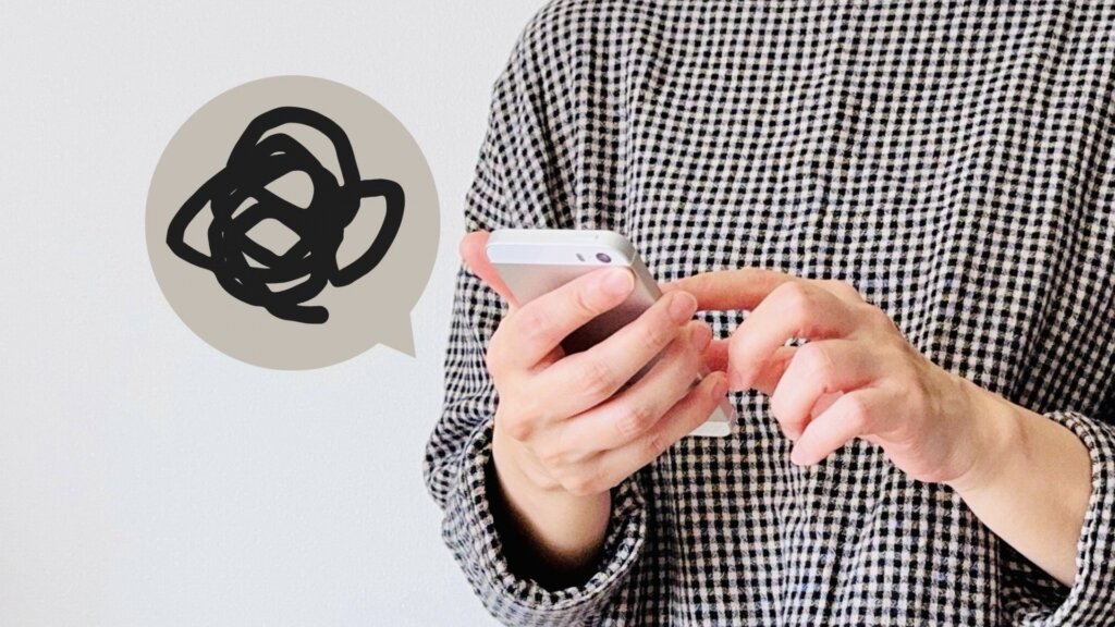 悩ましげにスマホを手にする人