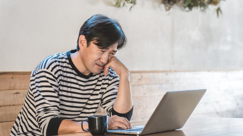 パソコンを見ながら悩む男性